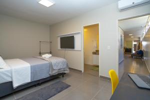 a bedroom with a bed and a desk and a television at Botanical House, bairro Jardim Botânico 3 de Bsb in Brasilia