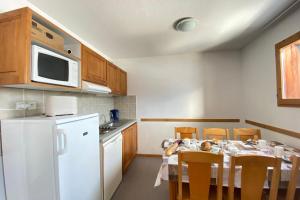 Il comprend une cuisine équipée d'une table avec des chaises et d'un réfrigérateur blanc. dans l'établissement Cosy nest near the SuperDévoluy ski resort, à Saint-Étienne-en-Dévoluy