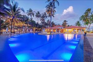 a large swimming pool with palm trees and a building at Flat no hotel jatiúca suítes Resort in Maceió