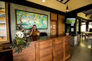 a woman sitting at a counter talking on a cell phone at Melheim Resort and Spa in Haputale