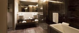 a bathroom with two sinks and a bath tub at COMO Alpina Dolomites in Alpe di Siusi
