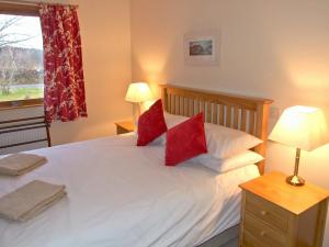 a bedroom with a white bed with red pillows at Balorrin in Contin