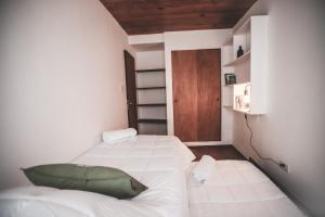 een kleine slaapkamer met 2 bedden en een houten deur bij Urban 1 Apartamento Bariloche in Bariloche