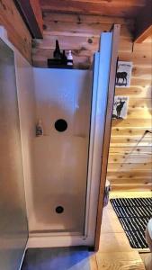 a white refrigerator in a room with a wooden wall at Alpine Retreat: Off-Grid Cabin Winter Adventure in Pemberton