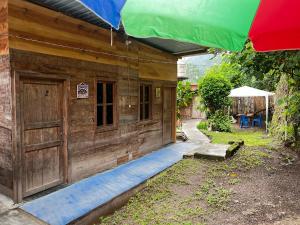 une maison en bois avec un parasol devant elle dans l'établissement Casa " MARY ", à Lanquín