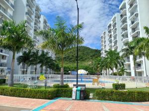 a resort with a pool and palm trees and buildings at Beatiful apartment in condo in Girardot