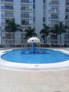 an empty swimming pool with an umbrella in front of a building at Beatiful apartment in condo in Girardot
