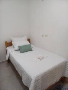 a white bed with a green pillow on it at Beatiful apartment in condo in Girardot