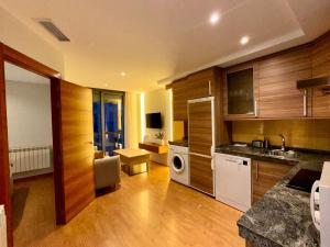 a kitchen with wooden cabinets and a living room at Apartamento Punto24 con acceso a Parking in Cáceres