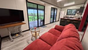 a living room with a red couch and a kitchen at Feng Shui Sugarcane Cabin in Proserpine