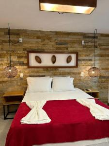 a bedroom with a large bed with a red blanket at Vila Biju Jeri in Jericoacoara