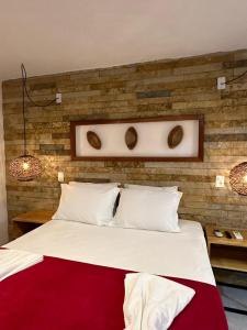 a bedroom with a large white bed with a brick wall at Vila Biju Jeri in Jericoacoara