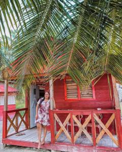 une femme debout devant un bâtiment rouge dans l'établissement Cabaña privada en Guna Yala isla diablo baño compartido, à Cagantupo
