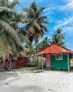 uma cabana vermelha e verde numa praia com palmeiras em Cabaña privada en Guna Yala isla diablo baño compartido em Cagantupo