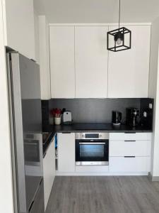 La cuisine est équipée de placards blancs et d'un four en acier inoxydable. dans l'établissement Apartament 33 Nad Iławką, à Iława