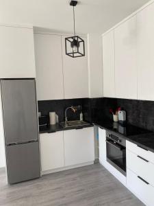 a kitchen with white cabinets and a stainless steel refrigerator at Apartament 33 Nad Iławką in Iława