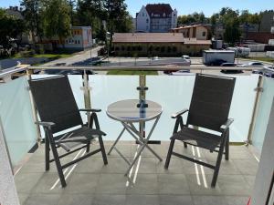 two chairs and a glass table on a balcony at Apartament 33 Nad Iławką in Iława