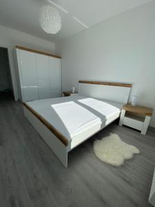 a bedroom with a large white bed and a rug at Apartament 33 Nad Iławką in Iława