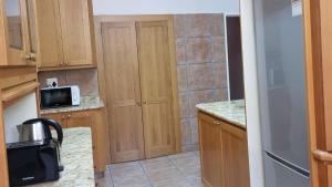 a small kitchen with wooden cabinets and a microwave at Kabana Family Home and Guest House in Cape Town