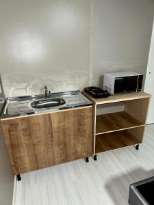 uma cozinha com um lavatório e um micro-ondas no balcão em Loft Lux 2 em Chapecó
