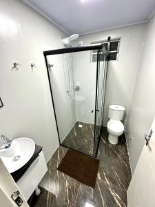 a bathroom with a glass shower and a toilet at Loft Lux 2 in Chapecó