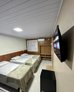 a room with two beds and a flat screen tv at Loft Lux 2 in Chapecó
