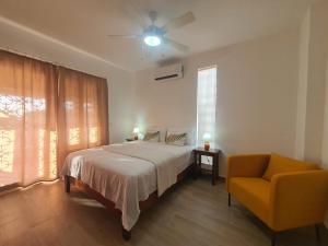 a bedroom with a bed and a chair and a ceiling fan at Apartamento bayahibe in Bayahibe