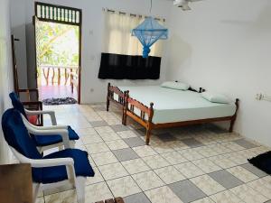 una camera con un letto e una sedia e una finestra di Temple Flower Guest a Kirinda