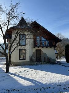una casa con techo de gambrel en la nieve en Цісарка en Mykulychyn