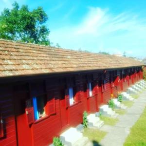 un edificio rojo con puertas rojas y asientos blancos en Pousada Avalon Paranapiacaba en Paranapiacaba