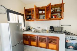 a kitchen with wooden cabinets and a stainless steel refrigerator at Bienvenue Chez NeEm Studio : ) (Douala-Ndogbong) in Douala