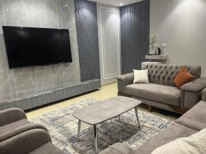 a living room with a couch and a flat screen tv at شقق النخبة غرفتين وصالة in As Sayl aş Şaghīr