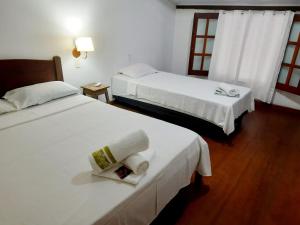 two beds in a hotel room with white sheets at BEACH HOUSE l in Itacaré