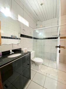 a bathroom with a toilet and a glass shower at BEACH HOUSE l in Itacaré