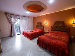 um quarto de hotel com duas camas e uma janela em Hotel el Ángel Taxco em Taxco de Alarcón