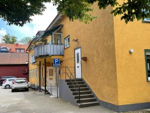 a yellow building with a white door and stairs on it at Bakgårdens Vandrarhem in Mariestad