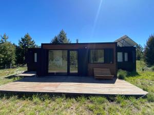 a tiny house in a field with a wooden deck at Meliquina Home in Villa Meliquina