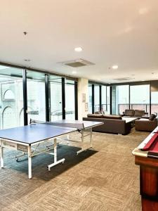 Habitación con 2 mesas de ping pong y sofá en entire 2BR Central Apt 1004, en Adelaida