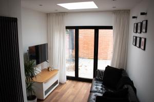 a living room with a couch and a television at SW Stay - Stylish One Bedroom with patio in London