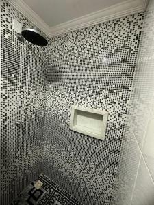 a bathroom with a shower with black and white tiles at Casa - Praia de Peroba in Maragogi