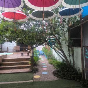 a row of umbrellas hanging over a garden with stairs at Pousada Caragua Poesia na Praia in Caraguatatuba