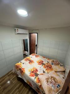 Un dormitorio con una cama con flores. en Casa - Peroba, en Maragogi