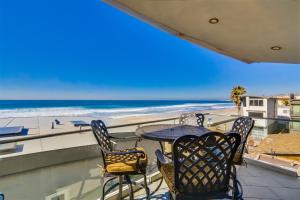 a balcony with a table and chairs and the beach at Ocean view, two-level condo with stunning view, decks, fast WiFi & fireplace in San Diego