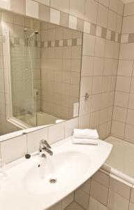 ein Badezimmer mit einem Waschbecken, einem Spiegel und einer Badewanne in der Unterkunft Kviknes Hotel in Balestrand