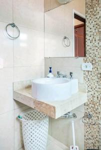 Un baño con un lavabo blanco y un espejo. en Casa Papai Noel, en Campos do Jordão