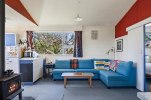 a living room with a blue couch and a stove at Sunlit Retreat - Te Horo Beach Holiday Home in Otaki