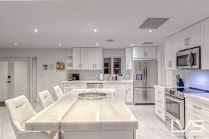 a large white kitchen with a table and chairs at Cascada-Luxe Resort Heated Pool HotTub Wlk 2 Beach in Fort Lauderdale