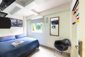ein Schlafzimmer mit einem blauen Bett und einem schwarzen Stuhl in der Unterkunft El Misti Hostel Ipanema in Rio de Janeiro
