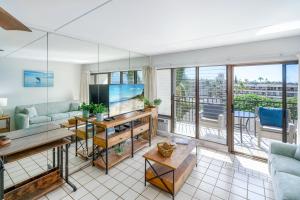 een woonkamer met een tv en een groot raam bij Kihei Akahi C-608 - Stunning Ocean Views, AC! in Wailea