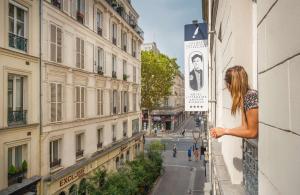Una mujer mirando por la ventana de un edificio en Hôtel Littéraire Arthur Rimbaud, BW Signature Collection en París